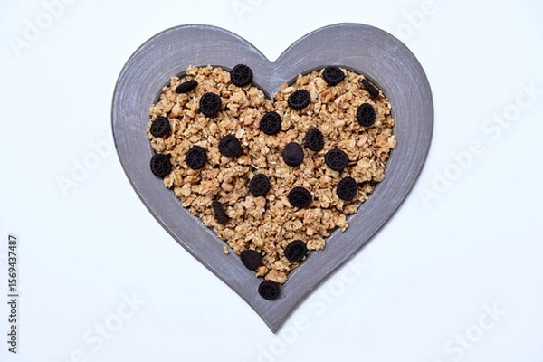 Fototapeta granola with chocolate cookies in a heart shaped frame on a white background