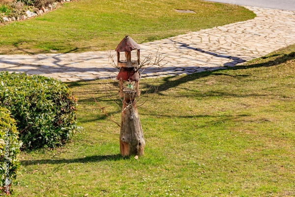 Fototapeta Rustic wooden birdhouse on a sunny lawn with stone path
