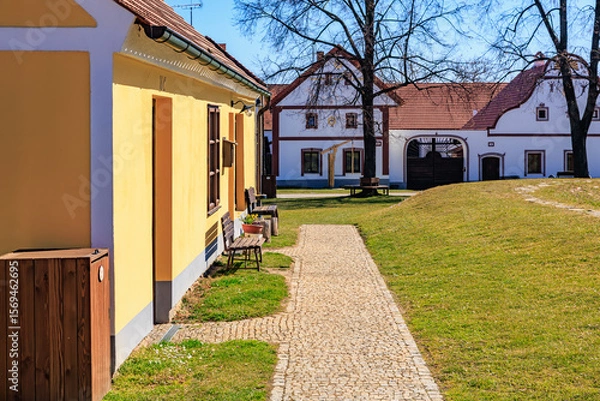 Fototapeta Charming village scene with traditional architecture and cobblestone path on a sunny day