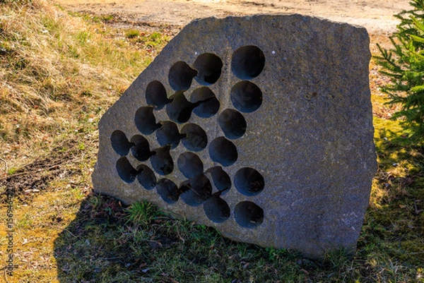 Fototapeta Abstract stone sculpture with circular holes in outdoor setting