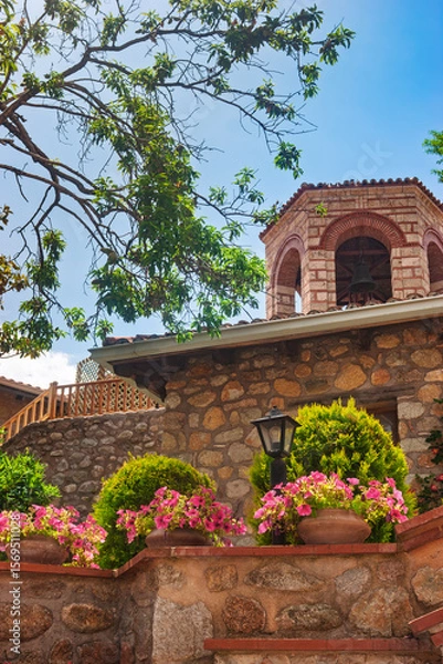 Fototapeta Monastery courtyard with potted flowers and bell tower in Meteora Greece