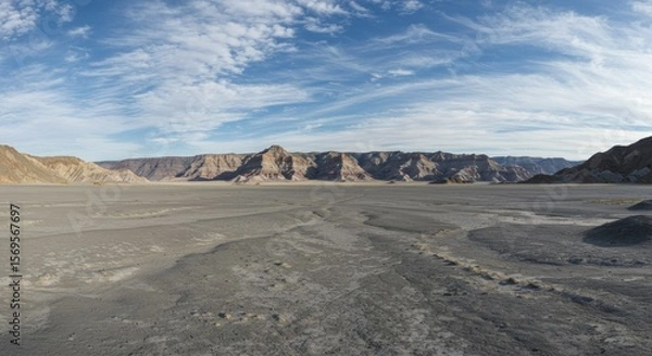 Obraz Vast Desert Landscape with Mesas and Cracked Ground Under Blue Sky.