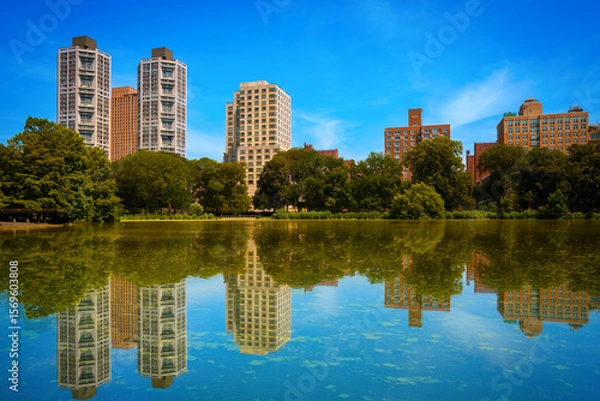 Fototapeta New York City skyline and Central Park landscape with building reflections over Harlem Meer Lake — a tranquil summer scene in Upper Manhattan