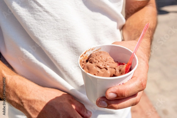 Fototapeta Man holding cup with scoop of sweet dessert chocolate ice cream in hand