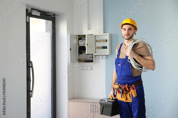 Obraz Młody elektryk z wiązką przewodów w pomieszczeniu