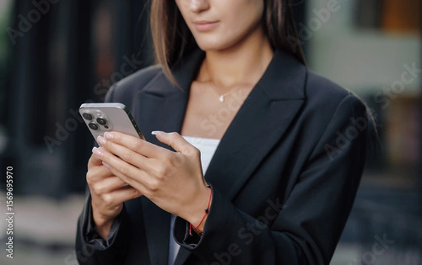 Obraz Hands of business woman using smartphone at city street