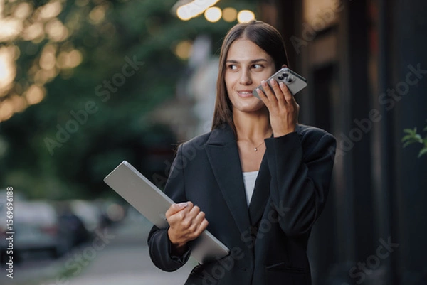Obraz Elegant business woman send a voice message in the city