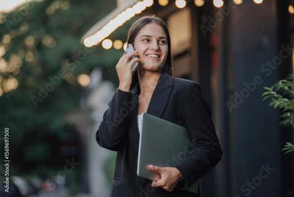 Obraz Elegant business woman talking by smartphone in the city