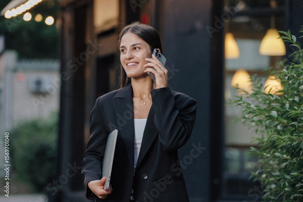 Obraz Elegant business woman talking by smartphone in the city