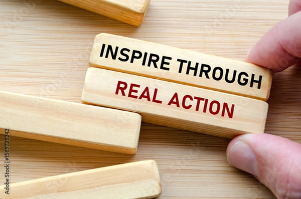 Fototapeta Inspire through real action message displayed on wood blocks, reflecting how true influence comes from doing rather than just speaking or commanding