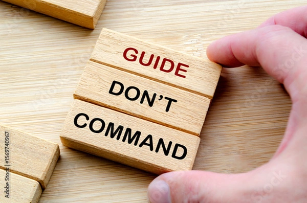 Fototapeta Guide, do not command phrase on wooden blocks, emphasizing mentorship, encouragement, and empowerment over authoritarian control