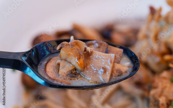 Obraz Spoon with cooked mushrooms in broth, close-up of Asian food. Macro photography with texture and warm tones. Ramen