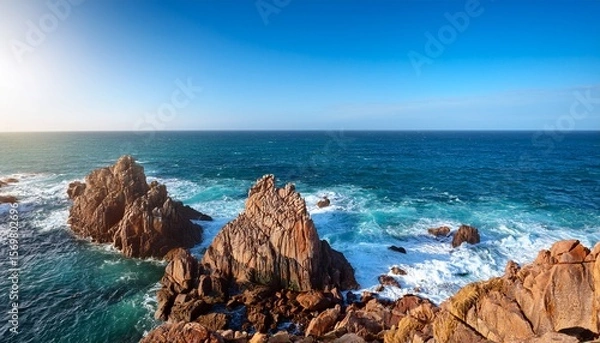 Fototapeta rugged coastal rock formations in sunlight with blue ocean and waves