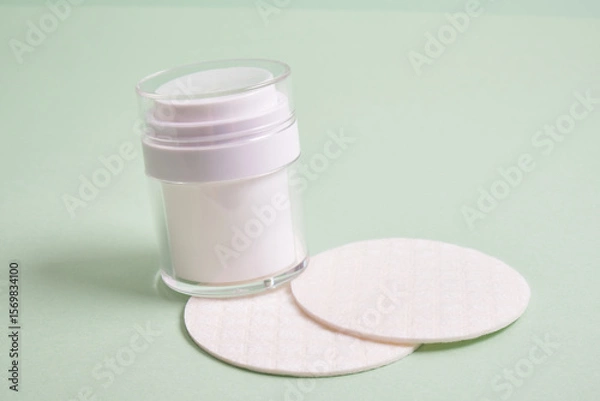 Obraz reusable skin care pads and white mock up bottle with pump dispenser for cosmetics on green background, pastel shades