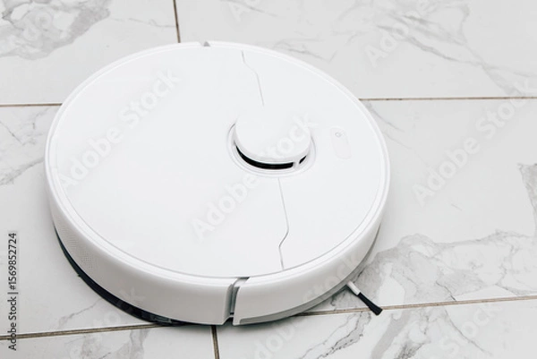 Obraz Robot vacuum cleaner operates on tiled floor during a bright afternoon in a modern home setting