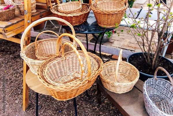 Obraz Woven baskets displayed on rustic wooden shelves at an outdoor market in spring