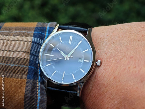 Fototapeta Man Wearing Elegant Wristwatch Outdoors. Man’s wrist wearing a sophisticated analog watch with a blue dial and silver case