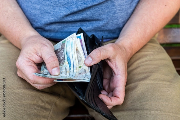 Fototapeta Counting Polish Zloty – Hands of a Man with Wallet and Cash.  A man in casual clothes holding and counting Polish zloty notes from a black leather wallet.