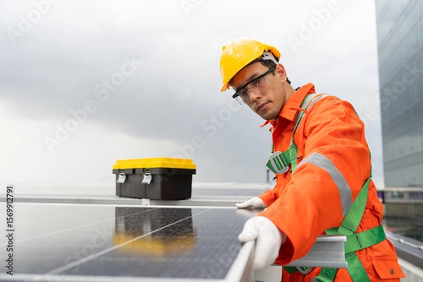 Obraz Solar panel rooftop, Rooftop solar power. Engineer or technician inspecting installation quality of solar power systems on rooftop of building. Male engineer checks solar panel on rooftop