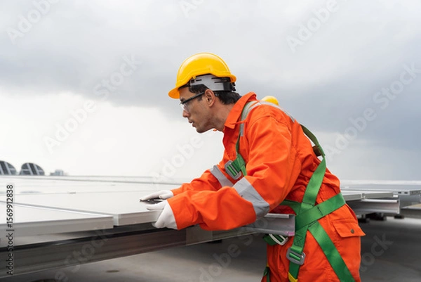 Obraz Solar panel rooftop, Rooftop solar power. Engineer or technician inspecting installation quality of solar power systems on rooftop of building. Male engineer checks solar panel on rooftop