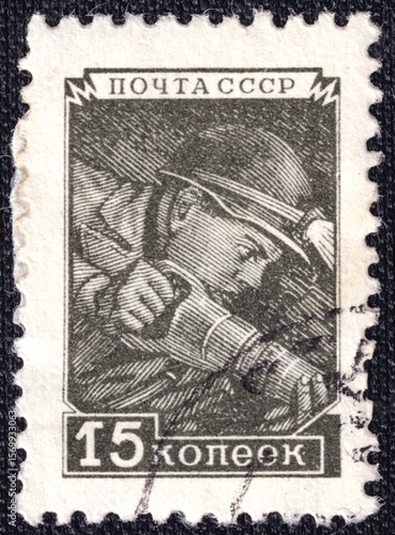 Fototapeta Miner in a mine extracting coal with Coal Hammer on a 1957 USSR postage stamp.