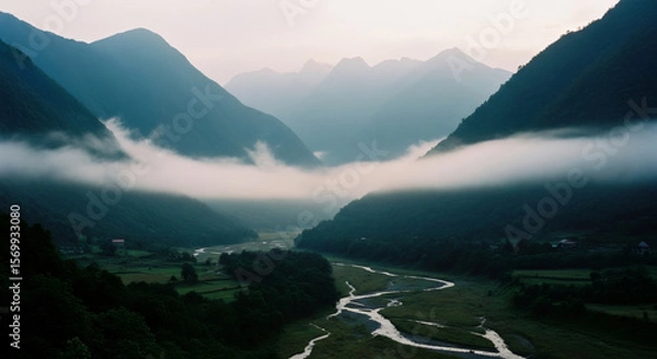 Fototapeta Misty valley with winding river at dawn. Foggy mountain landscape. Scenic nature view with low clouds. Tranquil outdoor scene for travel, adventure, and environmental concept