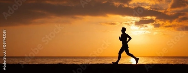 Fototapeta The runner silhouette against a beautiful sunset by the ocean shoreline.