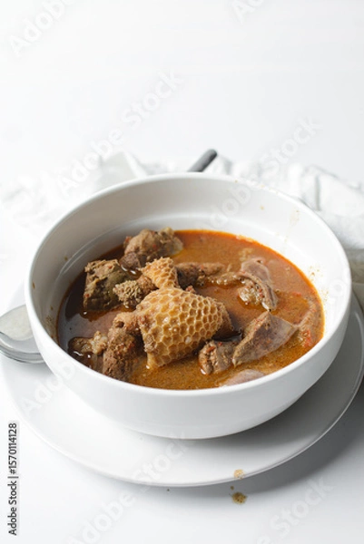 Obraz Overhead view of Nigerian goat pepper soup in a white soup plate, top view of goat meat pepper soup in a plate, traditional goat peppersoup in a white bowl