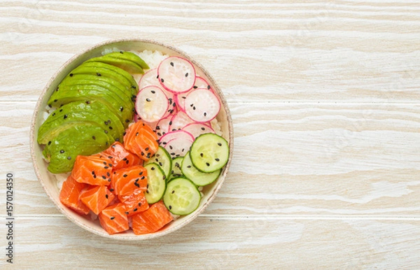 Obraz Poke bowl, a traditional hawaiian dish with diced raw salmon, avocado, vegetables served with rice and vegetables, a healthy meal on white wooden background, copy space