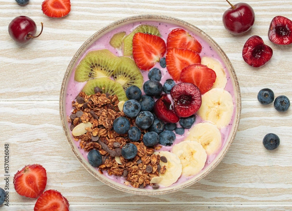 Obraz Vibrant acai bowl topped with fresh fruits like bananas, strawberries, kiwi, blueberries, cherries, crunchy granola for a healthy meal, breakfast or snack