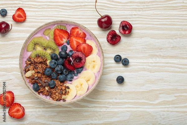 Fototapeta Vibrant acai bowl topped with fresh fruits like bananas, strawberries, kiwi, blueberries, cherries, crunchy granola for a healthy meal, breakfast or snack