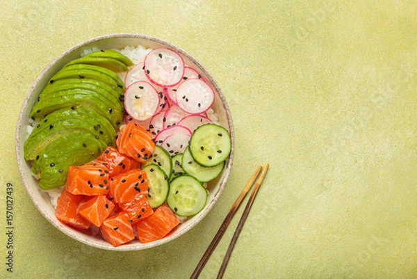 Obraz Poke bowl, a traditional hawaiian dish with diced raw salmon, avocado, vegetables served with rice and vegetables, a healthy meal on green background, copy space