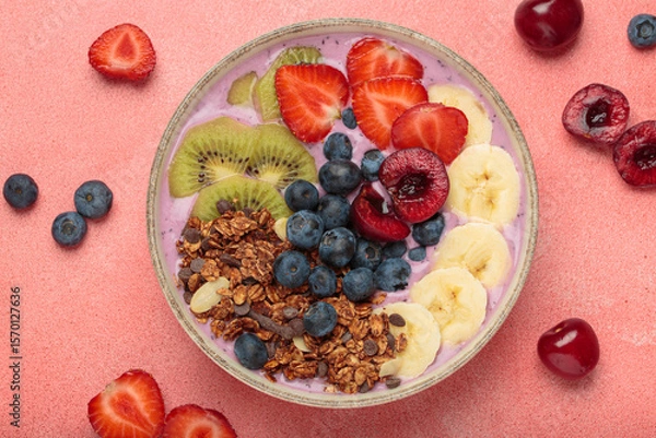 Obraz Vibrant and nutritious acai bowl topped with sliced kiwi, strawberries, blueberries, cherries, banana, and granola, a colorful and healthy meal or breakfast on a pink background