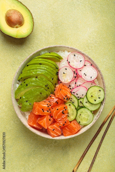 Obraz Poke bowl, a traditional hawaiian dish with diced raw salmon, avocado, vegetables served with rice and vegetables, a healthy meal on green background