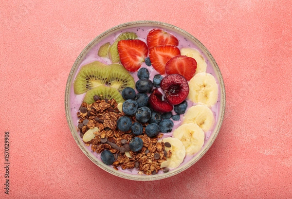 Obraz Vibrant and nutritious acai bowl topped with sliced kiwi, strawberries, blueberries, cherries, banana, and granola, a colorful and healthy meal or breakfast on a pink background