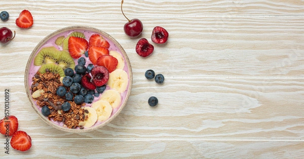 Obraz Vibrant acai bowl topped with fresh fruits like bananas, strawberries, kiwi, blueberries, cherries, crunchy granola for a healthy meal, breakfast or snack, copy space