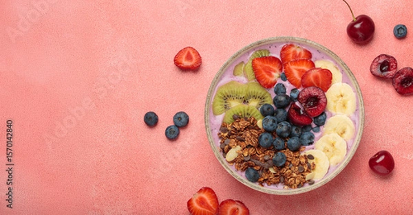 Obraz Vibrant and nutritious acai bowl topped with sliced kiwi, strawberries, blueberries, cherries, banana, and granola, a colorful and healthy meal or breakfast on a pink background, copy space