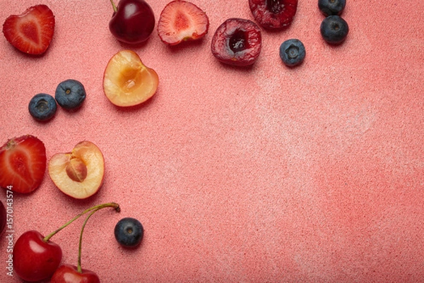 Obraz Vibrant arrangement of fresh fruit including strawberries, cherries, blueberries, and bananas on a textured pink surface with copy space
