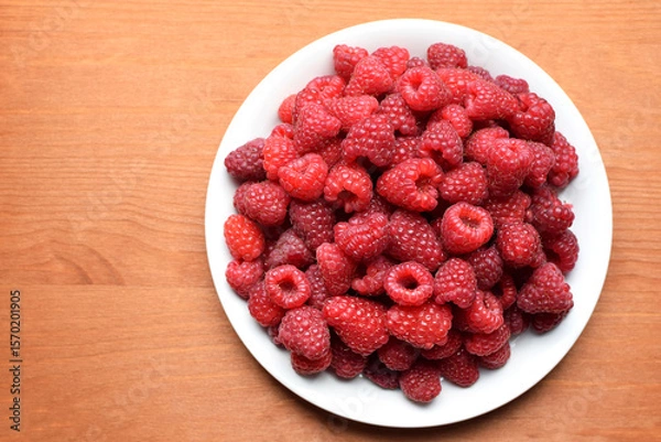 Fototapeta Ripe red raspberries on a white plate. Sweet raspberry background. Berries close-up. Healthy food. Copy space.