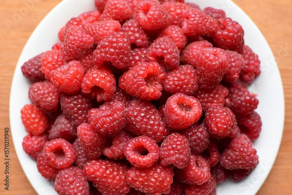 Fototapeta Ripe red raspberries on a white plate. Sweet raspberry background. Berries close-up. Healthy food