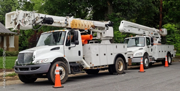 Fototapeta Front and side view of parked communication utility trucks in residential neighborhood. Horizontal.