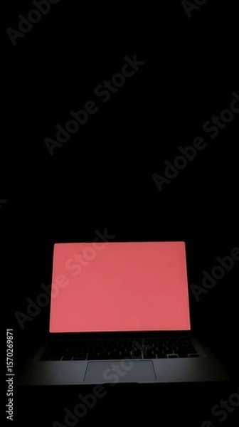 Fototapeta Laptop with a solid red screen in a dark setting.