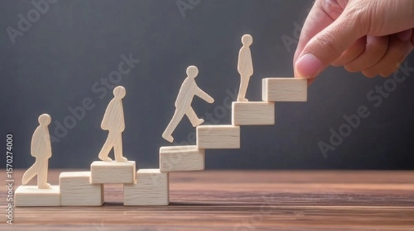 Fototapeta Wooden figures ascend stairs made of blocks, symbolizing growth, progress, and support, with a hand placing the final step.