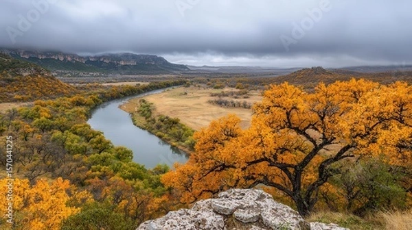 Obraz Peaceful autumn valley with golden trees, mistcovered hills, and a crystalclear river meandering through
