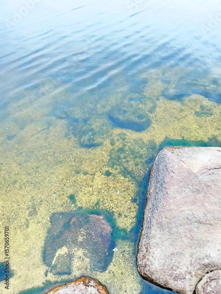 Fototapeta Amazing colorful background of the water surface of the Dnieper disturbed by a light wind over a stone bottom that shines through the water column.