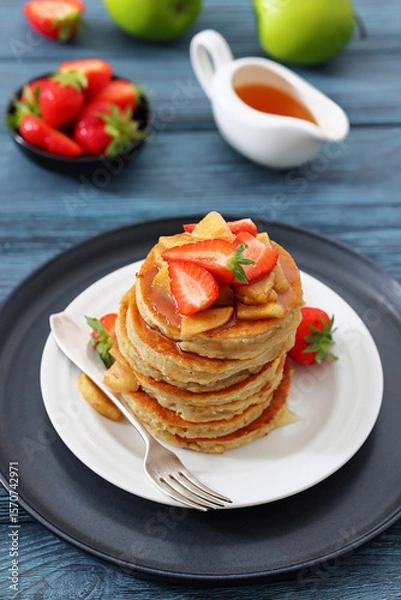 Fototapeta pancakes topped with apple slices and strawberries