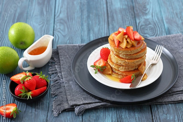 Fototapeta pancakes topped with apple slices and strawberries