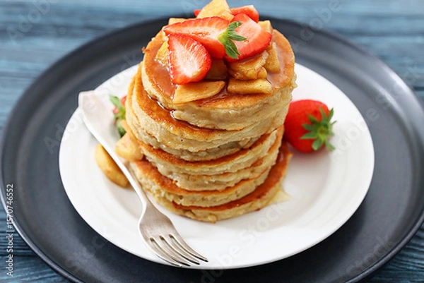 Fototapeta pancakes topped with apple slices and strawberries