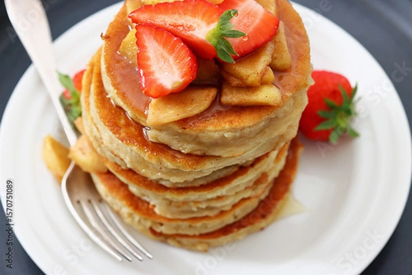 Fototapeta pancakes topped with apple slices and strawberries