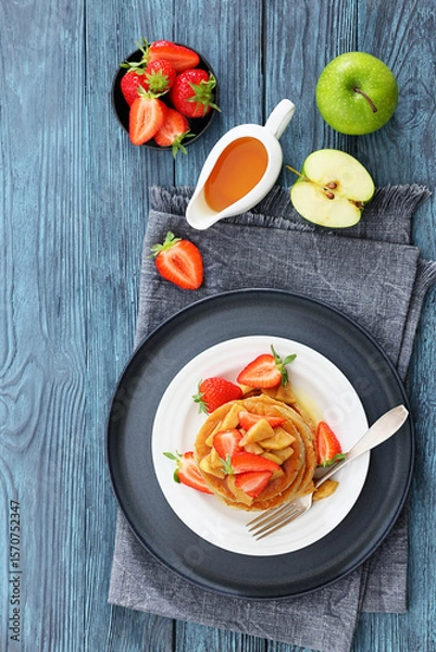 Fototapeta pancakes topped with apple slices and strawberries